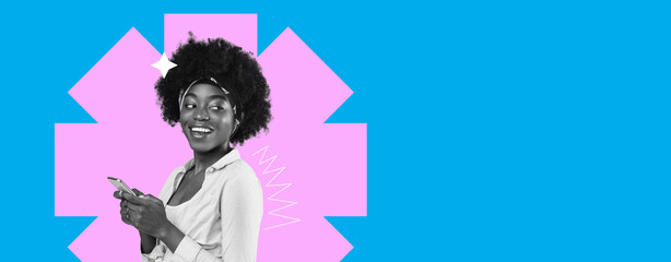 A young woman stands smiling while looking at her mobile phone. She appears happy and engaged. The...