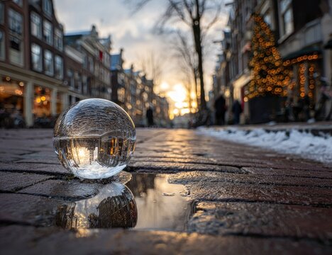 Glass sphere reflects canal houses and festive lights on a cobbled street