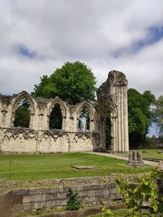 Fototapeta premium Ruins of ancient abbey with stone arches and green lawn under cloudy sky in England