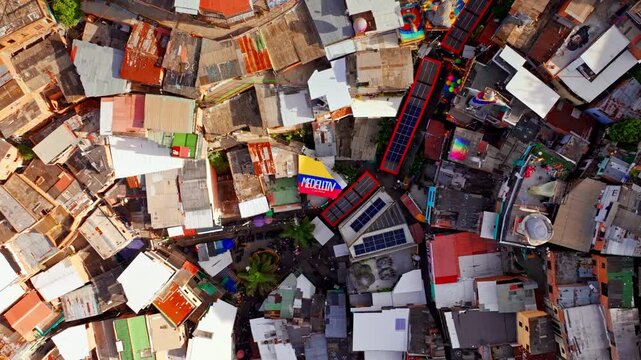 Top down drone view of Comuna 13 in Medellin, Colombia, capturing dense hillside housing, narrow streets, and the layered urban texture of this iconic neighborhood from above.
