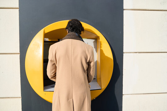 Adult man performing banking transaction at atm