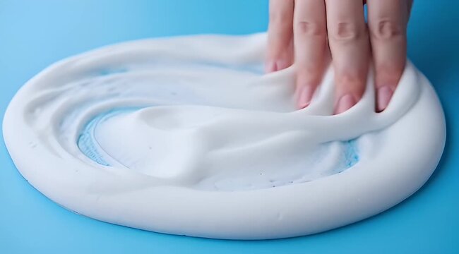 White slime texture with blue coloring and hand pressing down on it
