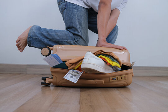 Person Packing Suitcase With Clothes And Travel Documents
