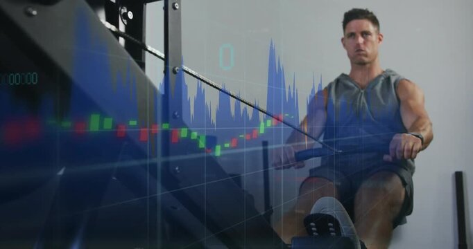 Rowing man starting pulling handle on erg at gym, wearing sleeveless hoodie, financial overlay