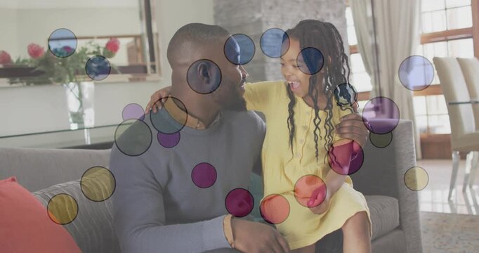 Child climbing onto dad's lap sparking bonding on couch for tech demo with bubbles covering frame