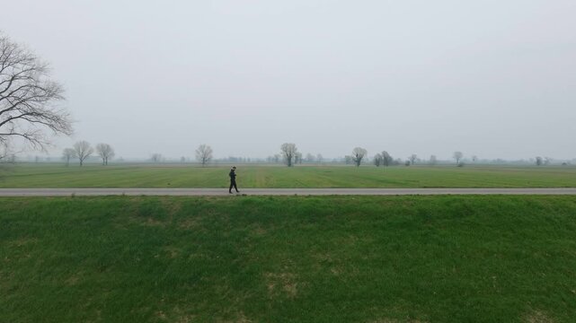 Pilgrim walking along the Via Francigena across the Lombardy countryside near Orio Litta, Italy. Drone aerial view