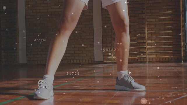 Woman training basketball handling ball appearing through legs dribbling particles data overlaying