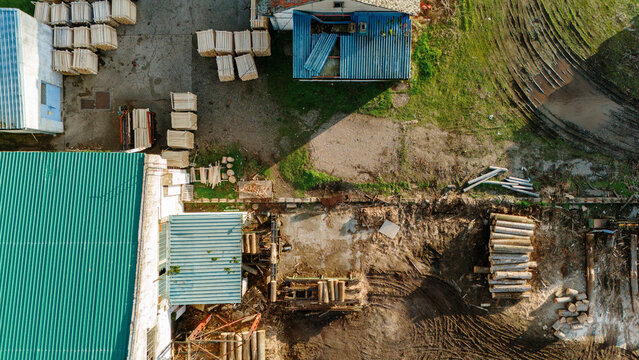 Aerial view of stacked lumber and industrial buildings casting long shadows, a stark contrast of textures and tones, Sremska Mitrovica, Vojvodina, Serbia.