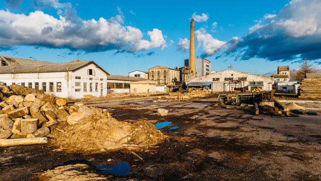 Aerial view of industrial buildings interspersed with piles of logs and dirt under a cloudy sky, Sremska Mitrovica, Vojvodina, Serbia.