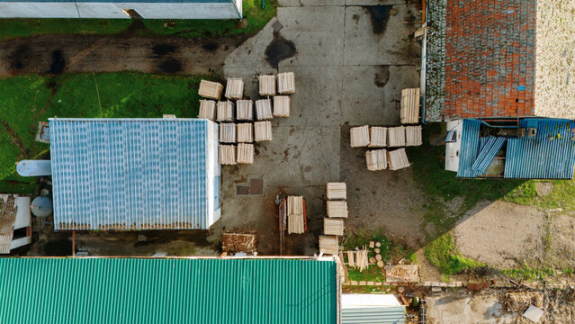 Aerial view of the rooftops and stacks of wooden planks create a geometric pattern against the concrete ground, Sremska Mitrovica, Vojvodina, Serbia.