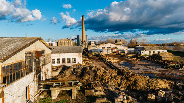 Aerial view of industrial buildings and lumber piles under a sky brushed with clouds, revealing the textures of the factory setting, Sremska Mitrovica, Vojvodina, Serbia.