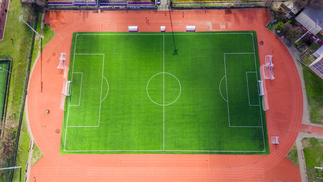 Aerial view of the verdant rectangle of a sports field, bordered by the terracotta track, a vibrant contrast against the urban landscape, Novi Sad, Vojvodina, Serbia.