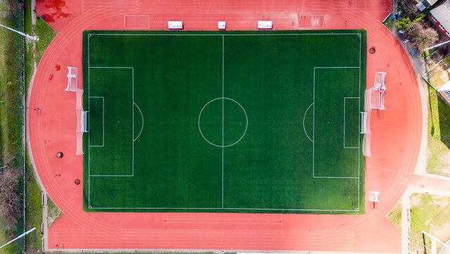 Aerial view of the vibrant green rectangle of the football field contrasts sharply with the surrounding red running track, Novi Sad, Vojvodina, Serbia.