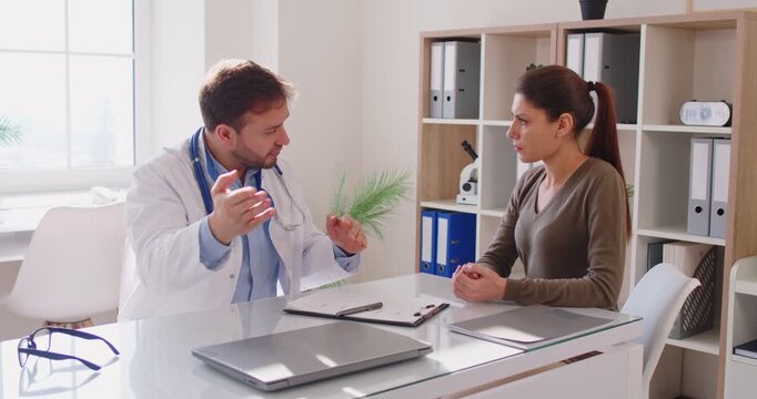 Doctor and patient during medical consultation in clinic. Healthcare provider explains diagnosis, treatment, and appointment advice. Clear concept: compassionate medical consultation and trust.