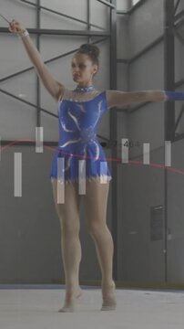 Vertical video: Teen rhythmic gymnast starting by sweeping ribbon, rotating on mat for competition