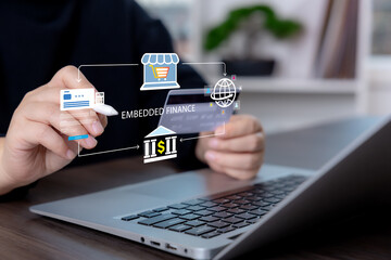 Person using credit card and laptop with embedded finance interface for digital payment, e-commerce checkout, online banking, and fintech transaction services.