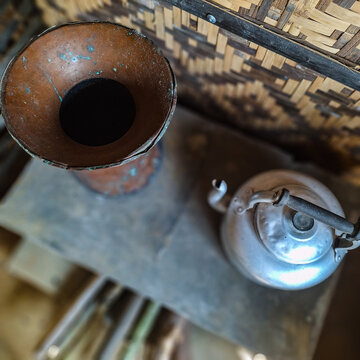 Old metal kettle placed on a traditional wood stove in a rustic bamboo kitchen. Represents authentic rural cooking culture using natural fuel.