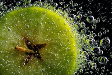 Macro shot lime slice in carbonated water with bubbles circling star anise center against dark backdrop, suitable for beverage branding and cocktail photography