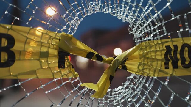 Shattered glass window secured with yellow hazard tape at night. Broken pane with caution barrier after accident or vandalism. Safety warning concept for danger zone alert.