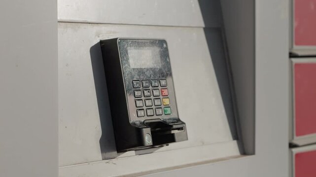 A POS terminal is mounted on a wall outside. It is exposed to the elements as it handles payment transactions. The device connects wirelessly for use.