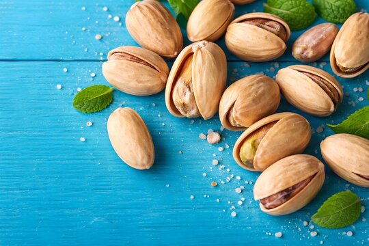 Close-up of roasted pistachio nuts in shell, a healthy vegan snack on a rustic blue wooden table.