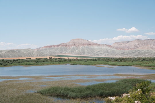 Landscape view of a lake and sedimentary hills under a clear blue sky