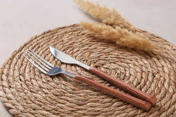 Table setting with silver cutlery and pampas grass on light grunge background