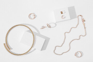 Beautiful golden necklace, bracelet, rings and earrings with podiums on white background