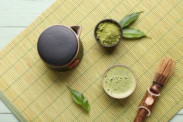 Traditional matcha tea set with whisk, teapot, frothy green tea and powder on bamboo mat, top view © Pixel-Shot