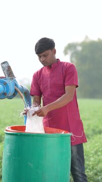 Indian farmer mixing water in fertilizer bottle 