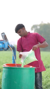 Indian farmer mixing water in fertilizer bottle 