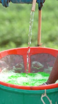 Farmer mixing water in pesticide or fertilizer powder at agriculture field 