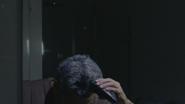 Middle-Aged Man Shaving Head with Electric Clipper in Bathroom