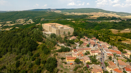 Obraz premium Aerial view of Lagopesole Castle, located in Basilicata, Italy. It is a medieval fort dating back to the time of Frederick II. A stone fortress perched on a lush green hilltop, overlooking the village