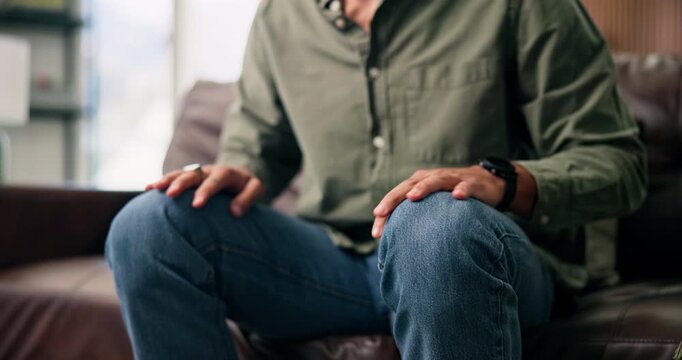 Anxiety, hands and man on sofa with stress, overthinking or mistake with wrong decision in lounge. Home, coping mechanism and nervous person with worry, trauma or stimming for mental health crisis