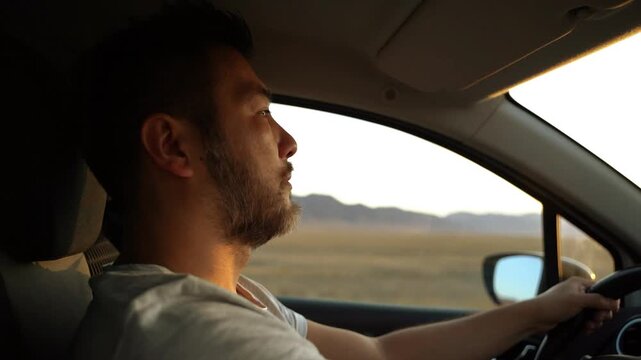 Pensive male driver looking ahead while driving during sunset road trip