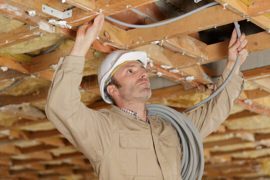 worker making mounting for an electric cable in ceiling