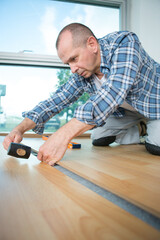 man laying laminate flooring with tools