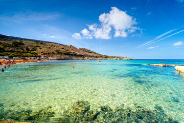 Fototapeta premium Paradise bay with azure Mediterranean Sea and tourists in water, Gnejna Bay, Għajn Tuffieħa, Malta.