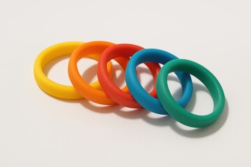Fototapeta premium Colored ring toy set arranged in a row on white surface minimal