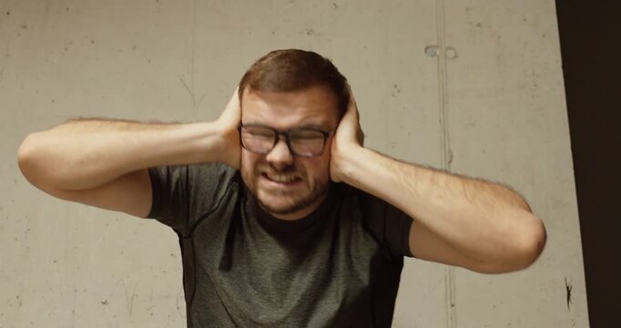 Close-up of a man covering his ears in fear during a loud explosion. Concept of war danger, rocket attack, shock, survival instinct, and civilian reaction to conflict.