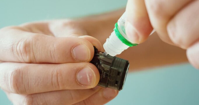 close-up of hands refilling e-liquid into a vape cartridge. Concept of e-cigarette maintenance, vaping accessories, nicotine liquid refill, and modern smoking alternatives.