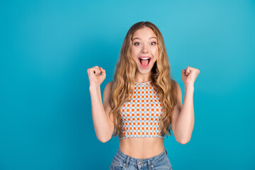 Young stylish woman celebrates success with a bright blue background and excited expression