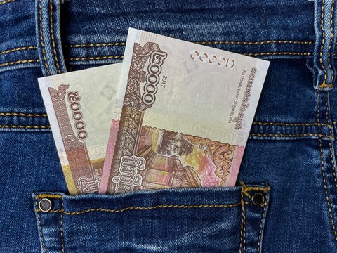 Close-up of Cambodian riel banknotes in the back pocket of blue jeans. Conceptual concepts of cash, personal finance, everyday expenses, saving, and budgeting.