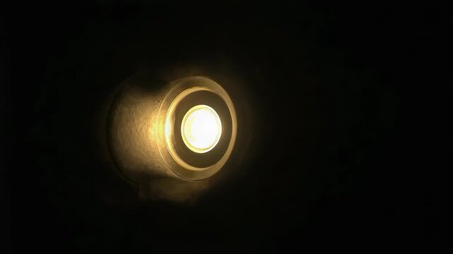 Glowing recessed ceiling light in dark room showing shifting halo, reflector ring, bulb, dust haze