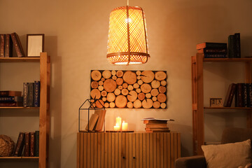 Interior of stylish room with wooden cabinet, glowing candles and bookshelves at evening © Pixel-Shot
