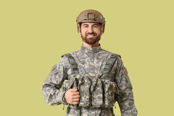 Naklejka premium Young happy male soldier in uniform on green background