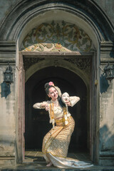 Obraz premium Beautiful woman in Burmese traditional dress performing ancient mask dance at old temple.