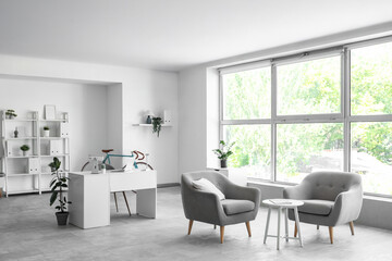 Fototapeta premium Interior of home office with workplace, bicycle and armchairs
