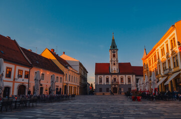 Fototapeta premium The historic main square of Varaždin in Croatia featuring the town hall and traditional buildings with red tile roofs. Many of the historic houses on the square host restaurants and cafes.
